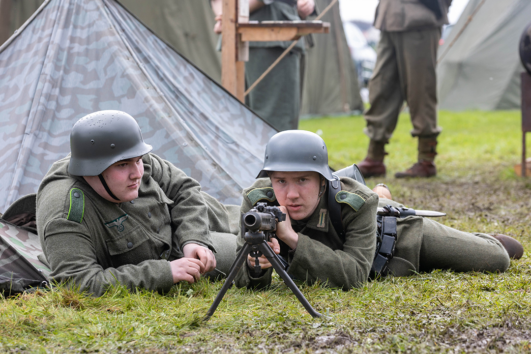 A WWII soldier lying on the floor with his colleague takes aim with a rifle on a rifle stand during a re-enactment at the Weston-super-Mare Military History Weekend